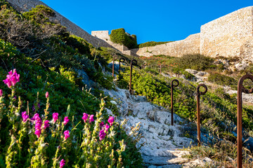 Old ruins of fortress Fortaleza de Belixe from behind, with rusty railing posts lining a eroded...