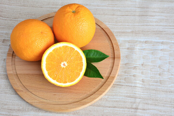 A wooden plate with oranges and green leaves on it, close-up