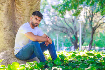 木の根元に座り微笑むインド人男性