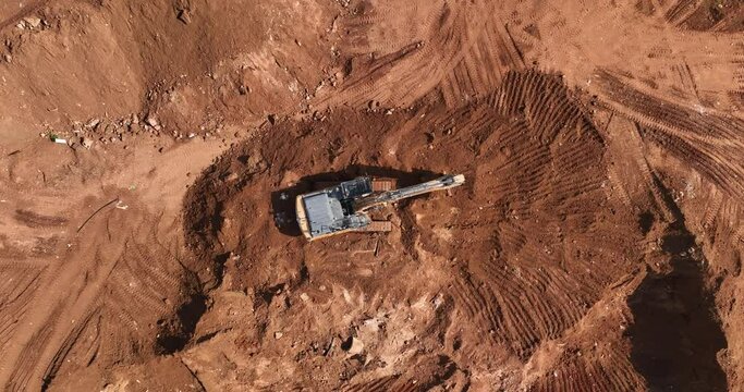 Aerial footage of Wheel Loader and a bagger working on a hill at a construction site and preparing the area for construction work. Filmed in C4K Apple ProRes 422 HQ