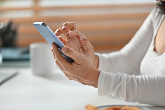 Cropped image of senior woman hand texting messages, enjoying chatting in social on smartphone