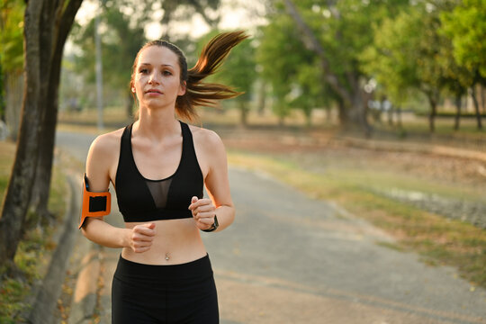 Image of attractive fitness woman jogging in the park with sunrise light. Fitness, sport and healthy lifestyle concept