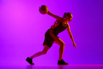 Fototapeta na wymiar Young girl, concentrated female basketball player in motion, dribbling ball, training against white studio background. Concept of professional sport, hobby, healthy lifestyle, action and motion