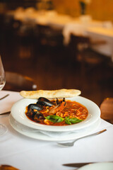 Appetizing Italian soup with seafood in a large white plate. Shrimps, mussels, octopuses. Restaurant serving food.