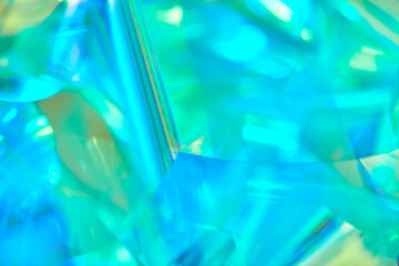Close-up of ethereal pastel neon mint, turquoise, blue, green holographic metallic foil background....