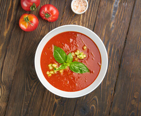 Gazpacho soup with tomatoes and basil on wooden table. Top view flat lay