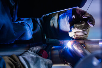 Men's hands closeup with argon welding machine. Welding of stainless steel pipes.