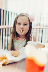 Young girl eating french fries in fast food restaurant
