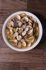 braised fresh White Sea clam shell in Chinese wine ginger onion and scallion soup in white bowl on wood table luxury halal food fine dining restaurant seafood menu