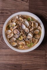 braised fresh White Sea clam shell in Chinese wine ginger onion and scallion soup in white bowl on wood table luxury halal food fine dining restaurant seafood menu