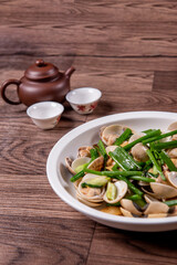 braised fresh White Sea clam shell in Chinese wine ginger onion and scallion soup in white bowl on wood table luxury halal food fine dining restaurant seafood menu