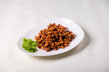 grilled golden deep fried baby squid cuttle fish octopus and cucumber in fresh honey spicy fish gravy sauce in white plate on wood table luxury halal food fine dining seafood restaurant appetiser menu