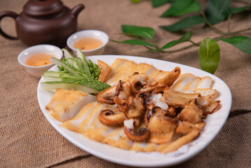 grilled golden deep fried baby squid cuttle fish octopus and cucumber in fresh honey spicy fish gravy sauce in white plate on wood table luxury halal food fine dining seafood restaurant appetiser menu