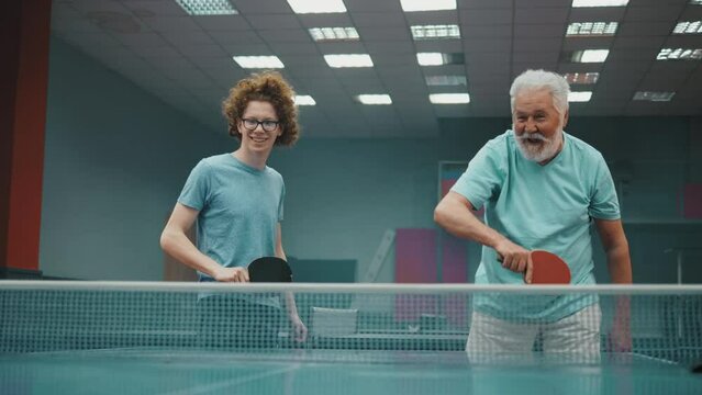 Old man and his teen grandsoon  playing table tennis doubles and winning
