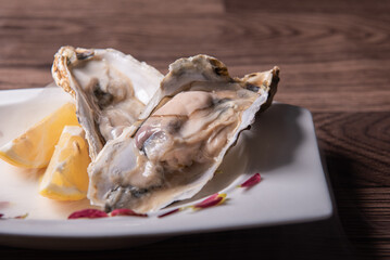 fresh western seafood raw big oyster shell with lemon in white cold plate on wood table luxury halal food fine dining asian restaurant chinese banquet halal food menu