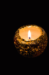 Burning golden candle. Dark background, selective focus.