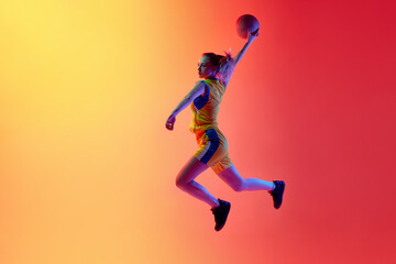 Fototapeta na wymiar Slam dunk. Dynamic image of active female basketball player in motion during game throwing ball, playing against white studio background. Concept of professional sport, hobby, healthy lifestyle