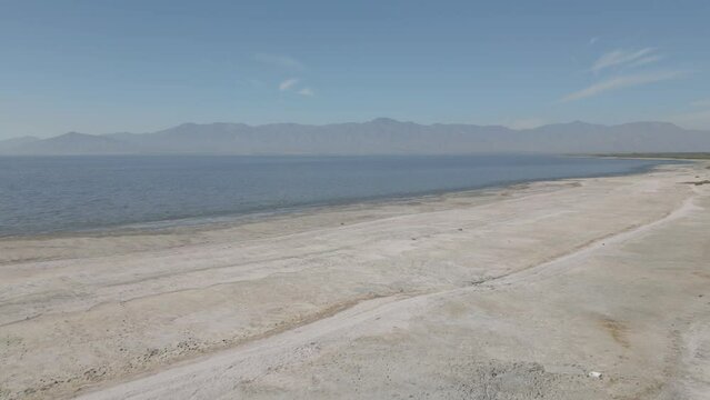 Drone footage od saline Salton Sea with deserted shore in Clifornia with mountains in the background