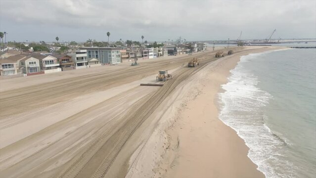 Aerial view of heavy equipments pushing sand raking pier in Seal Beach, California, USA