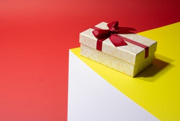Closeup of a small jewellery gift box with a bow on it on a colorful surface