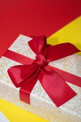 Vertical shot of a small jewellery gift box with a bow on it on a colorful surface