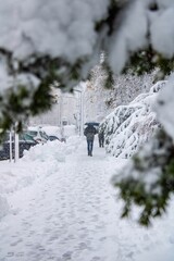 Vertical shot of a person walking with an umbrella in a snowy weather