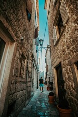 Vertical shot of a man walking along a narrow alley between the buildings