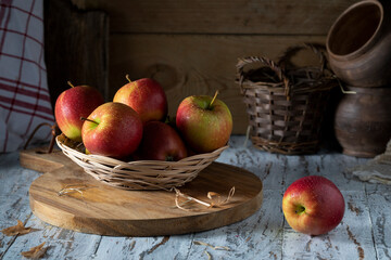 Red apples in a light wicker straw plate on a wooden table