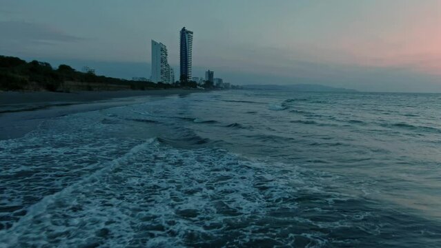 Aerial of calm sea waves rolling on Tonsupa beach at sunset in Ecuador.