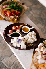 A set of Italian snacks for a buffet. A variety of cheeses, cold cuts bruschetta, pickled cucumbers, tomatoes on a wooden background
