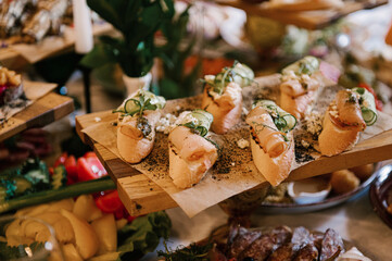 A set of Italian snacks for a buffet. A variety of cheeses, cold cuts bruschetta, pickled cucumbers, tomatoes on a wooden background