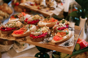 A set of Italian snacks for a buffet. A variety of cheeses, cold cuts bruschetta, pickled cucumbers, tomatoes on a wooden background