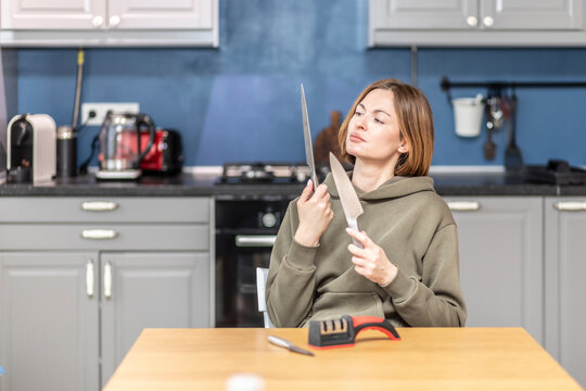 Close-up of woman sharpening knife with special knife sharpener at home