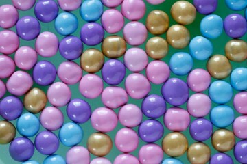Top view shot of small colorful circle-shaped candies on a green surface