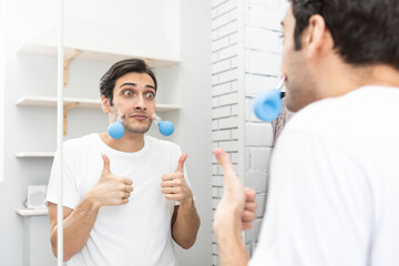 Handsome man standing in front of the mirror and doing facial massage with vacuum cups. Skin care...