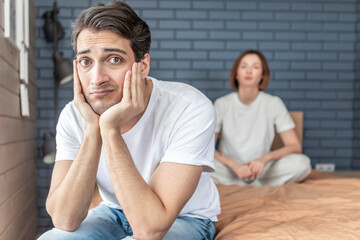 Frustrated and depressed man sitting on the edge of the bed after conflict with his wife because of his erectile dysfunction problem
