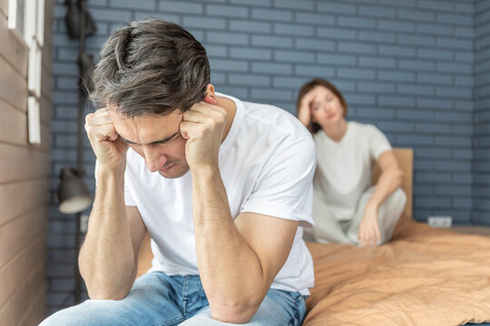 Frustrated and depressed man sitting on the edge of the bed after conflict with his wife because of his erectile dysfunction problem