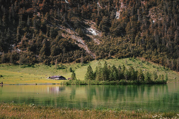 The traditional wooden house is located on a hill near the lake in the Nationalpark Berchtesgaden,...