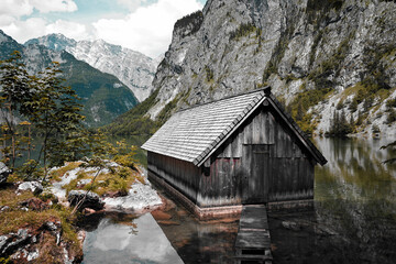 View of traditional old wooden boat house at scenic Lake Obersee and clouds in summer of the Nationalpark Berchtesgaden, Bavaria, Germany.
