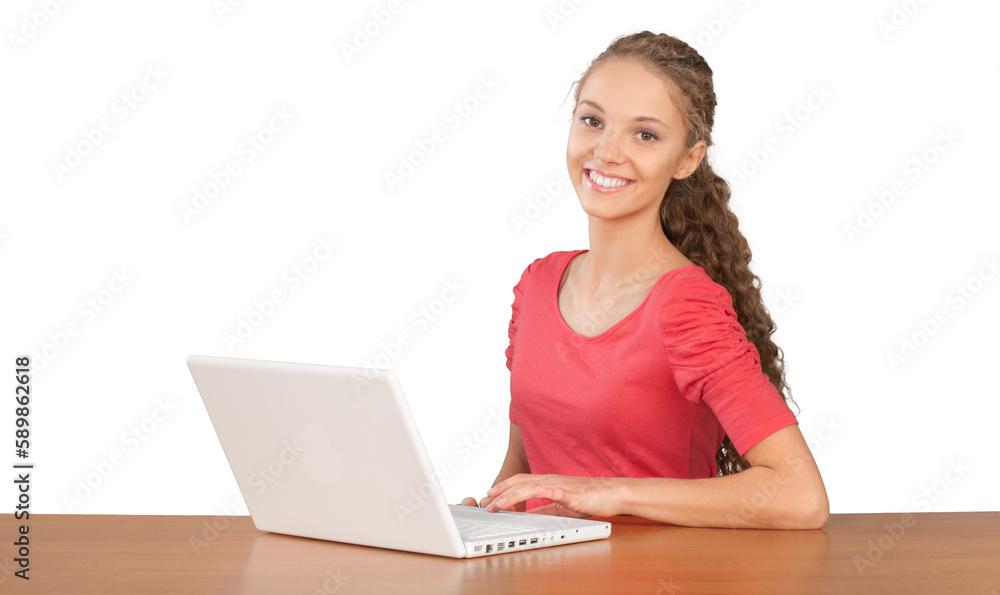 Wall mural girl sitting behind desk and using laptop - isolated