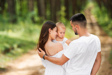 Mom, dad and daughter on summer walk. Happy family resting in nature.