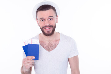 Handsome funny young traveler tourist man in summer clothes and hat  holding passports and tickets isolated on white background. Passenger traveling on weekend. Air flight journey concept