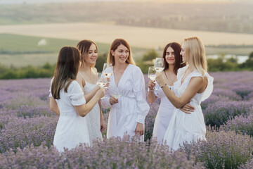 Beautiful young happy women in dresses are resting in a summer lavender field.	