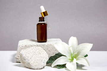 Spa and wellness setting with stones, lily flower and oil sereum for face beauty concept