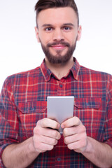 Handsome happy caucasian young bearded man using smartphone or cell phone for calls, social media, mobile application online isolated on white background