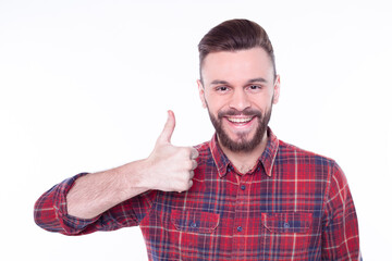 Attractive cheerful young man wearing checkered shirt standing isolated over white background and showing thumb up