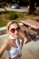 Casual blonde with sunglasses chilling outside in nature at summer holiday. Selfie like shot. Travel, holiday, leisure, lifestyle concept.