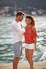 A young couple in love is having romantic moments while walking on the dock on the seaside. Love, relationship, holiday, sea