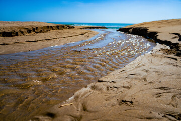 CINEMATIC SMALL RIVER FLOWS INTO OCEAN SEA COAST IN SPAIN CLOSE