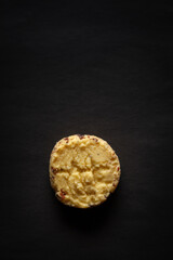 One whole wheat chip cookie on a black background. Top-down view. Food Flat lay.